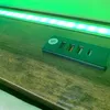 A close-up of a green combination lock with four dials on a wooden surface, with green LED lights in the background. Náhled obrázku produktu