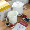 A yogurt maker with its accessories and packaging on a wooden surface. Náhled obrázku produktu