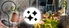 A collage of images showing solar-powered watering can garden lights, some illuminated and placed in a garden setting, others in a close-up view. A circular graphic with four black star shapes is overlaid in the center. Anteprima dell’immagine prodotto