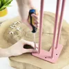 A person is using a screwdriver to attach a pink hairpin leg to a wooden surface. Podgląd zdjęcia produktu