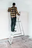 A person is standing on a ladder and painting a wall. Náhled obrázku produktu
