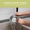 Hands washing a metal juicer component under running water in a sink. Produktbild-Vorschau