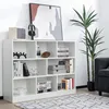 A white bookshelf filled with books and decorative items, placed against a white wall. A large abstract painting hangs on the wall above the bookshelf. A tall potted plant stands to the right of the bookshelf. Produktbild-Vorschau
