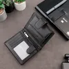 An open black leather wallet is displayed on a dark gray surface, with a notebook and pen in the background. Produktbild-Vorschau