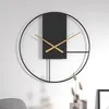 A modern wall clock with a black metal frame and gold hands, displayed on a white wall. Produktbild-Vorschau