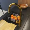 A close-up view of a modern kitchen sink area with a gold faucet, a fruit basket with oranges, and a wooden cutting board. Podgląd zdjęcia produktu