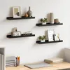 Four black wall shelves mounted on a white wall, each displaying various decorative items. Podgląd zdjęcia produktu