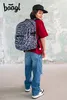 A young person wearing a backpack and casual clothing stands in front of a textured wall. Podgląd zdjęcia produktu