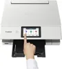 A hand is shown pressing a button on the touchscreen of a white Canon PIXMA TS8751 printer. Podgląd zdjęcia produktu