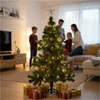 A family is decorating a Christmas tree in a living room. Produktbild-Vorschau