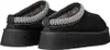 A pair of black UGG slippers with a decorative trim and thick soles are shown from the back. Voir les images du produit