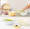 People preparing food in a kitchen with multiple colorful bowls. Produktbild-Vorschau