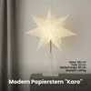 A white star-shaped paper lamp is displayed on a gray cabinet next to a gray curtain. Podgląd zdjęcia produktu