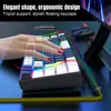 A hand is shown interacting with a gaming keyboard that has RGB lighting. The keyboard is angled, and a tablet stand is visible in the background. Produktbild-Vorschau