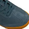A close-up view of the toe of a blue suede sneaker with a brown rubber sole. Anteprima dell’immagine prodotto