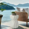 A white ceramic garden stool with a twisted design is placed on a patio next to an outdoor sofa, with a scenic view of mountains and the sea in the background. Anteprima dell’immagine prodotto