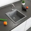A kitchen sink with a faucet, countertop, and some vegetables. Anteprima dell’immagine prodotto