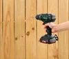 A hand holding a cordless drill and drilling a hole in a wooden fence. Produktbild-Vorschau