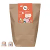 A brown paper bag with a colorful label and two coffee capsules in front. Produktbild-Vorschau