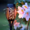 A solar garden torch is shown next to blooming flowers. Produktbild-Vorschau