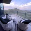 A balcony with outdoor furniture overlooking a mountainous landscape at sunset. Produktbild-Vorschau