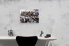 A framed painting of superheroes sitting on a ledge above a city is displayed on a concrete wall above a desk. Produktbild-Vorschau