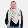 A woman wearing a beige knitted scarf. Produktbild-Vorschau