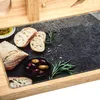 A close-up view of bread slices, olives, and rosemary on a dark surface, framed by a wooden border. Náhled obrázku produktu