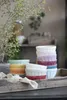 A collection of colorful ceramic bowls stacked on a rustic wooden tray, with a small green plant in the background. Produktbild-Vorschau