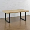 A wooden table with black metal legs is shown against a white brick wall and a wooden floor. Podgląd zdjęcia produktu
