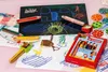 Children's drawings and art supplies are spread across a pink surface. Voir les images du produit