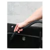 A hand holding a flexible black hose over a black sink. Produktbild-Vorschau