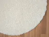 A close-up view of a white, shaggy rug on a wooden floor. Náhľad obrázku produktu
