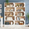 A modern, multi-level bookshelf filled with books and decorative items, set against a blue wall. Produktbild-Vorschau