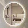 A round illuminated mirror in a modern bathroom setting, reflecting a shower and toiletries. Anteprima dell’immagine prodotto