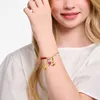A close-up shot of a young woman's arm wearing a charm bracelet. Produktbild-Vorschau