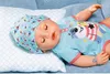 A baby doll lying on a pillow and a blue blanket. Produktbild-Vorschau