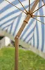 Close-up view of an umbrella's wooden pole and spokes, with blue and white stripes visible in the background. Produktbild-Vorschau