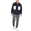 A man wearing a navy and white jacket and gray joggers. Produktbild-Vorschau