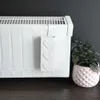 A white radiator water evaporator with heart decorations is shown next to a potted plant. Voir les images du produit