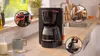 A Bosch coffee maker on a kitchen counter with inset images showing how to add coffee grounds, wash parts, and pour coffee. Anteprima dell’immagine prodotto