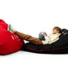 A young person lounging on a black beanbag chair with a basketball, next to a red beanbag chair. Podgląd zdjęcia produktu