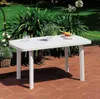 A white plastic table with items on it, placed on a patio in a garden setting. Náhľad obrázku produktu
