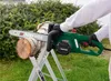 A person is using an electric chainsaw to cut a log outdoors. Produktbild-Vorschau