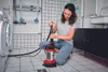 A woman is using a submersible pump in a laundry room or basement. Anteprima dell’immagine prodotto