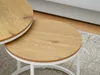 A close-up view of two round nesting coffee tables with wooden tops and white metal legs, placed on a patterned rug. Náhľad obrázku produktu