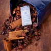 A close-up shot of dried fruit and cinnamon sticks spilling out of a blue bag, with a desiccant packet visible. Produktbild-Vorschau