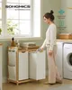 A woman is using a laundry basket with two compartments in a laundry room setting. Produktbild-Vorschau