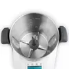 A top-down view of the interior of a white and gray thermo-multicooker, showing the blades and measurement markings inside the stainless steel bowl. Produktbild-Vorschau