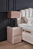 A bedroom scene featuring a bed, nightstand, and lamp. Produktbild-Vorschau